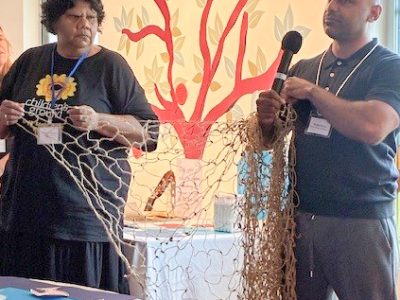 Phil and Veronica holding the net in front of fish table vertical